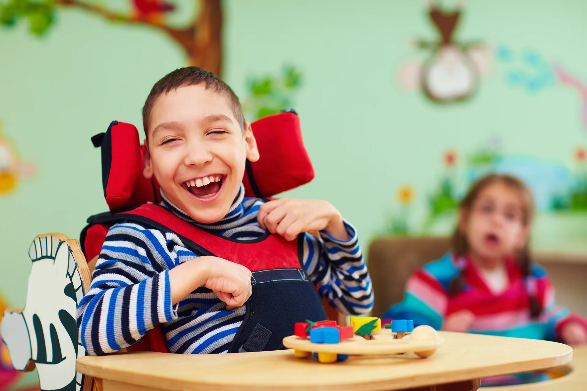 Young boy with special needs smiling while playing with learning toys at school